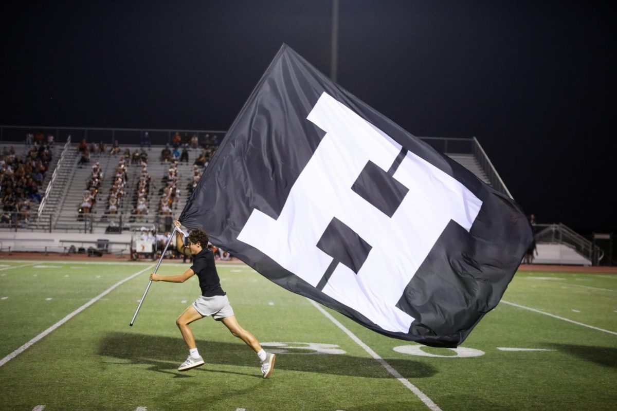 Freshman Ryan Lambert runs a flag across the field to spell out “VHS” after the first quarter.