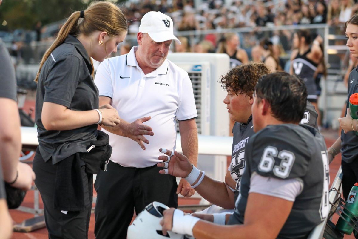 Assisting Doc Shivers with an injury, junior Caroline Erickson prepares to help the varsity football players.