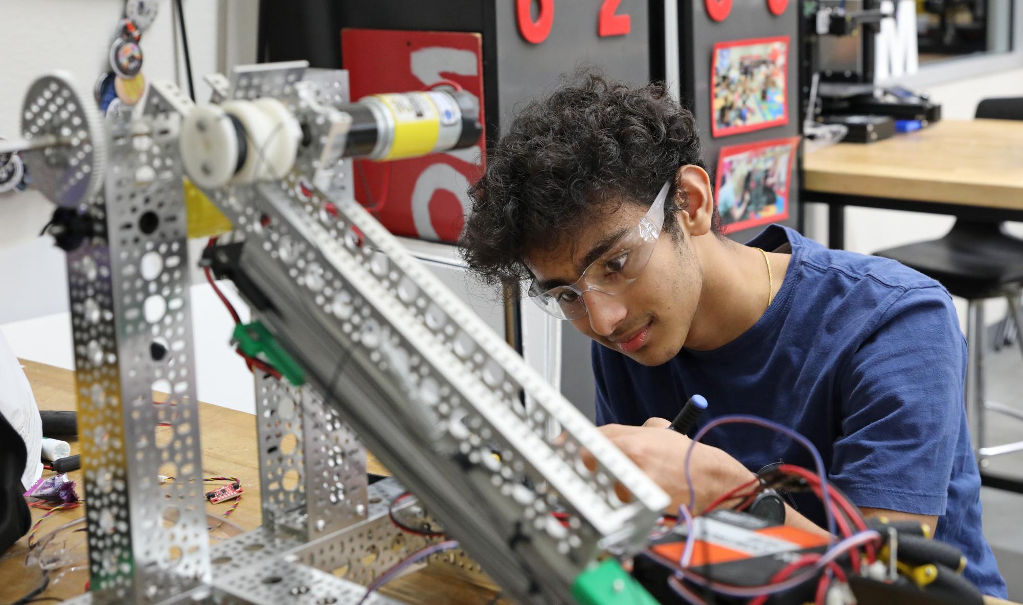 Senior Nipun Nagendra adjusts the alignment of the bevel-geared Mecanum Wheels for more precise motion control. This assembly was part of FTC 6210 Stryke's preparation for their first competition. 